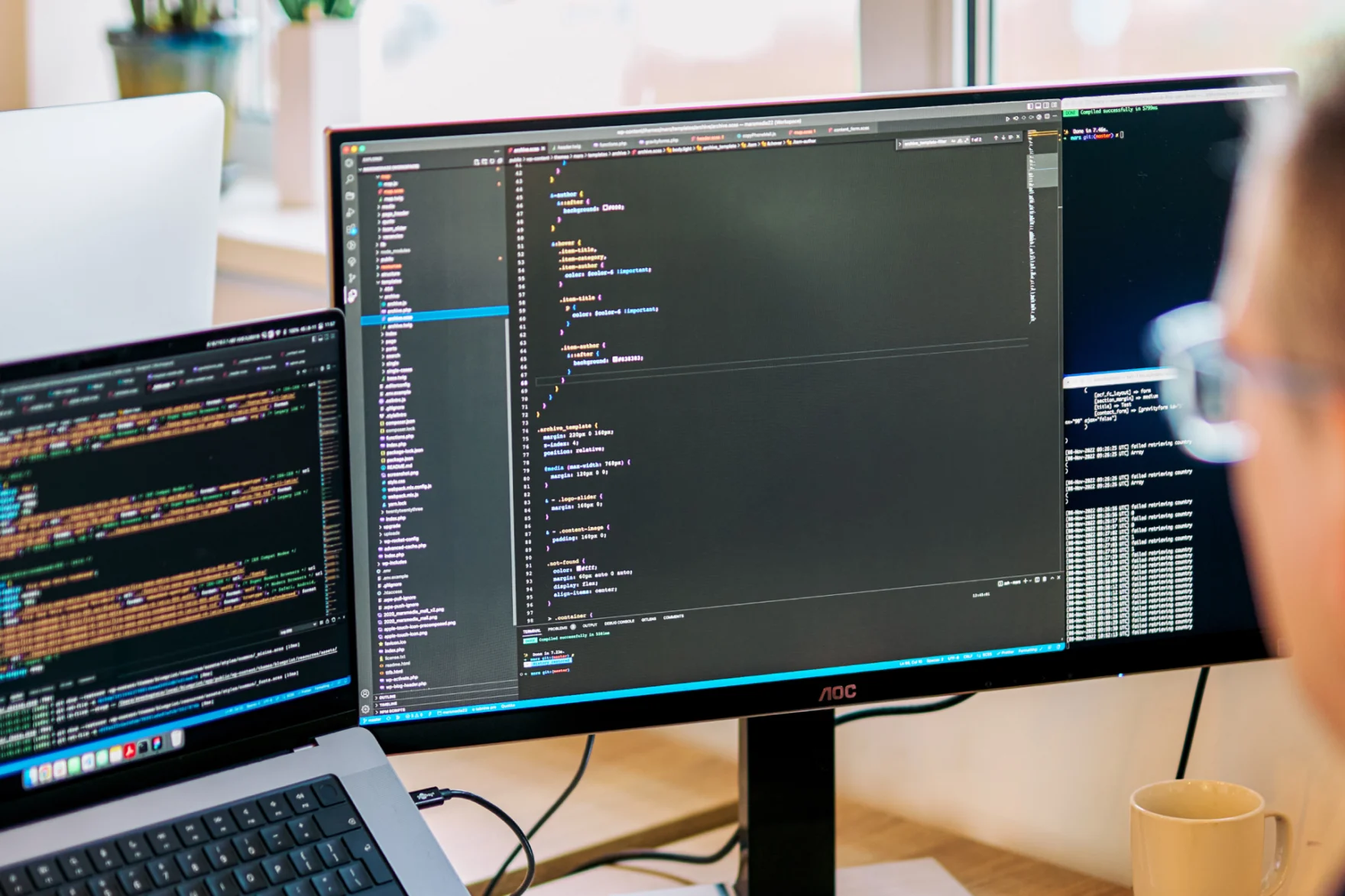 Developer reviewing website code across dual monitors during a website optimization project