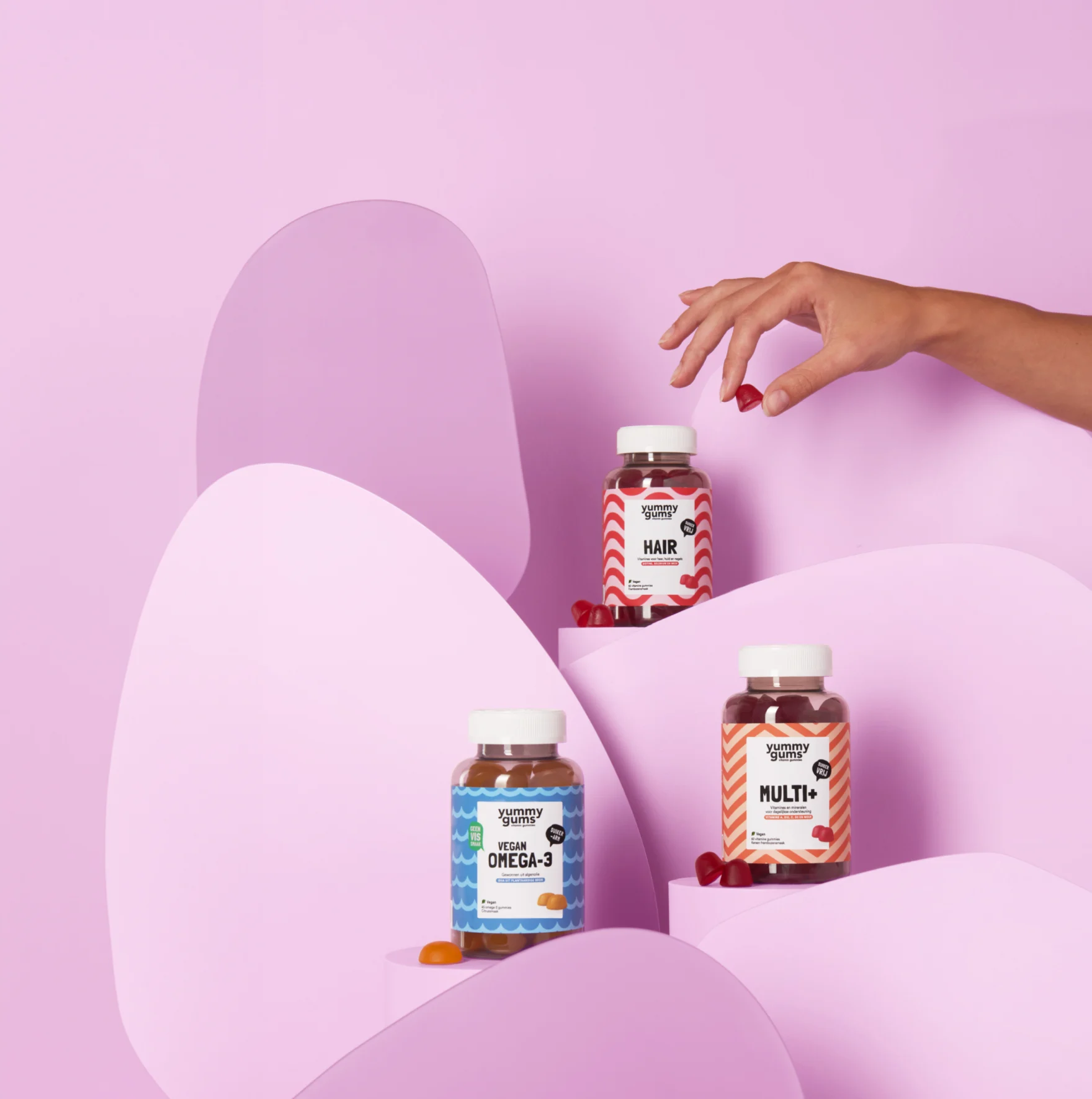Flesjes met Yummygums-gummies voor het haar, omega-3 en Multi+-vitamines, uitgestald op roze voetstukken