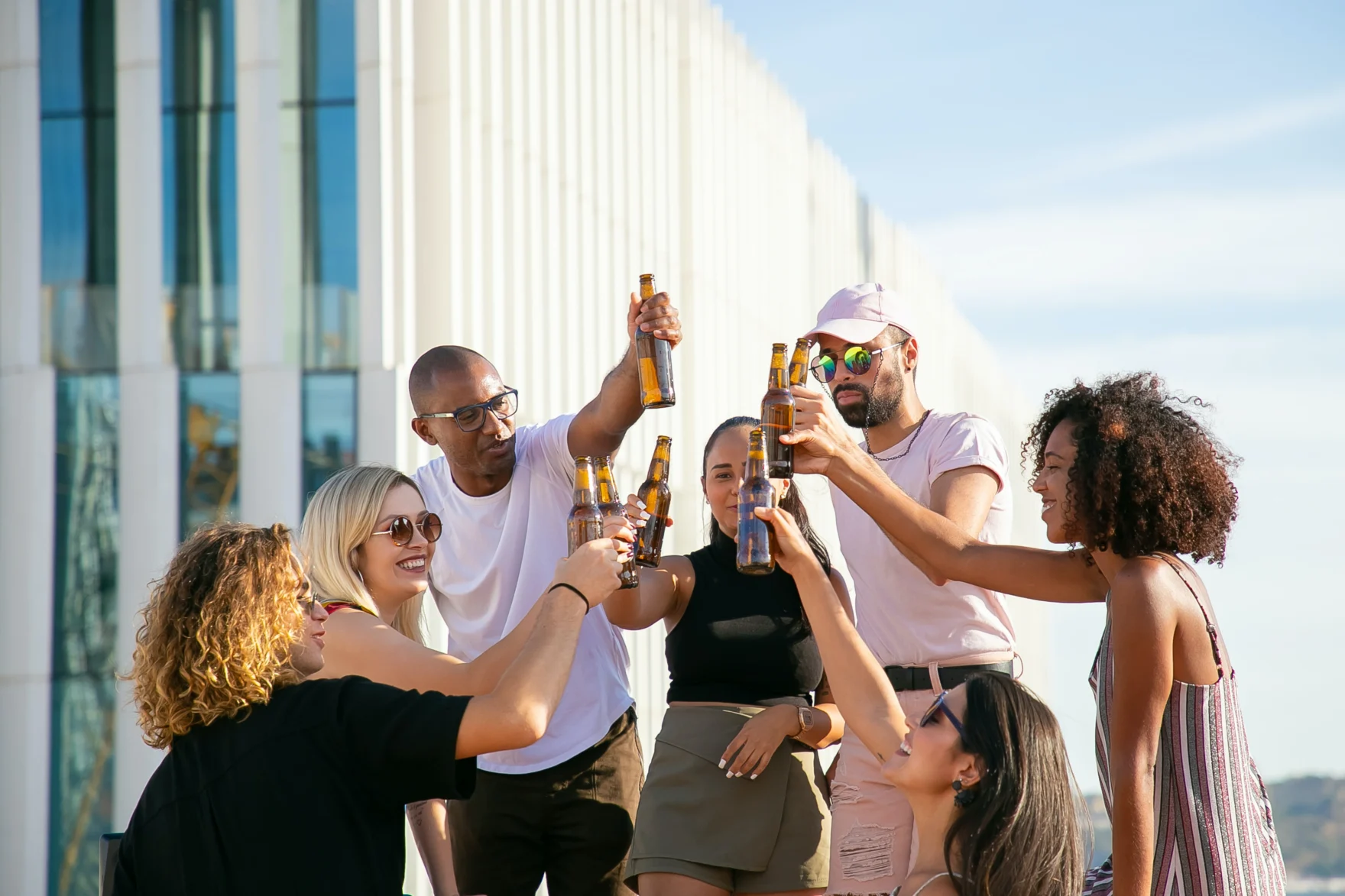 Group of friends toasting beer bottles on a rooftop terrace