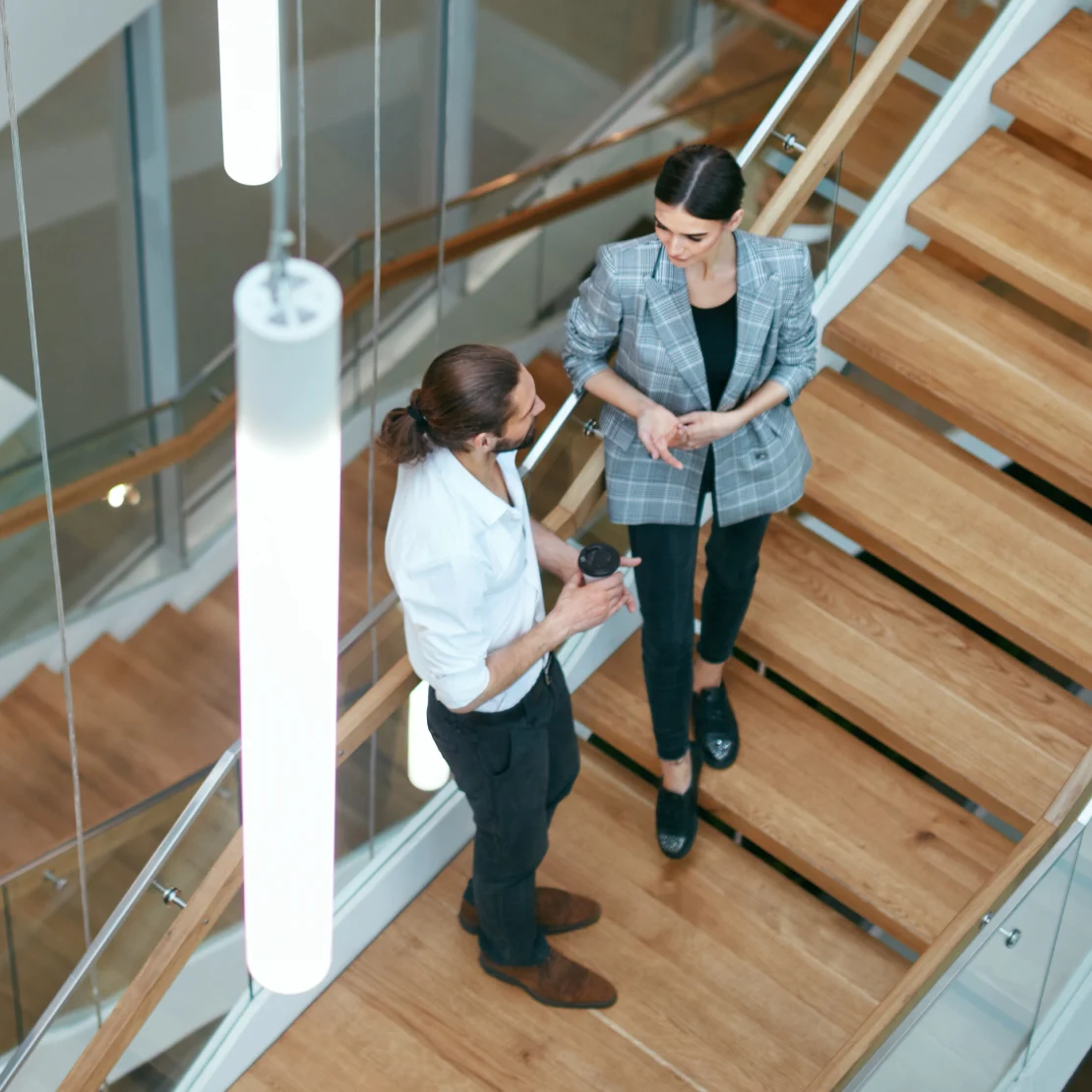 Two colleagues talking on a wooden staircase in a modern office