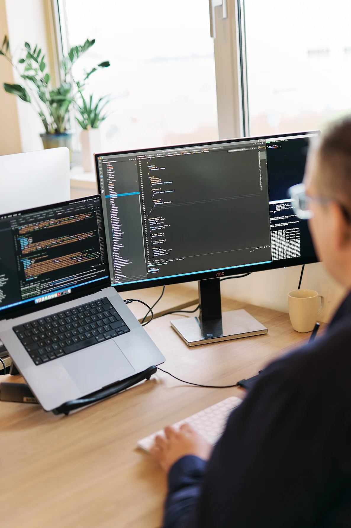 Developer reviewing code on dual monitors for website hosting and maintenance
