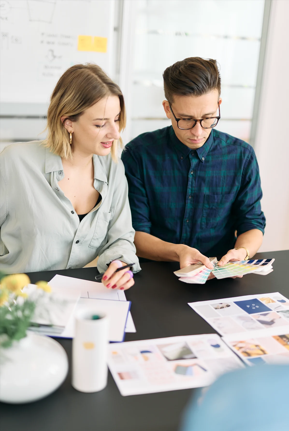 Two designers reviewing color swatches and mood boards for marketing materials