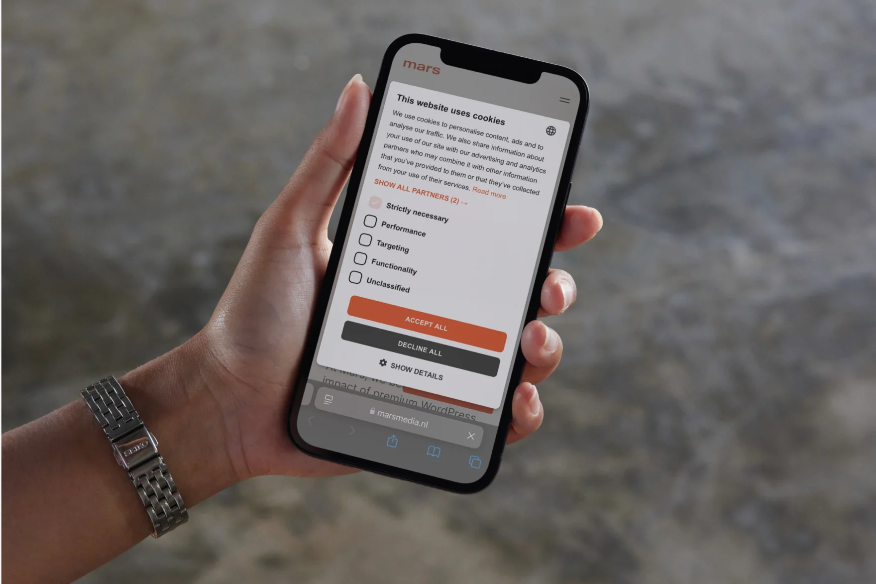 Hand holding a phone showing the Mars website cookie consent banner