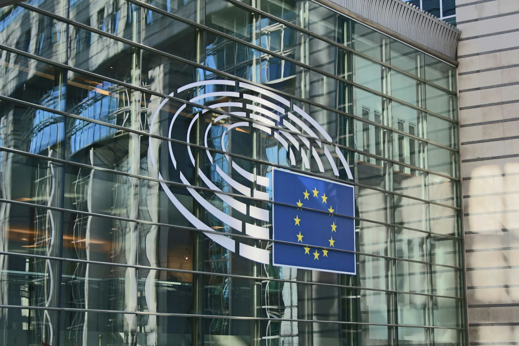 Close-up of the European Parliament building facade with the EU flag and parliament emblem