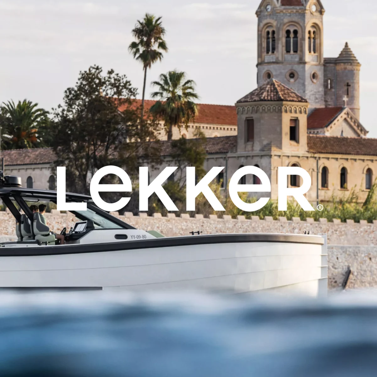Lekker boat branding overlay on a coastal Mediterranean photo of a yacht