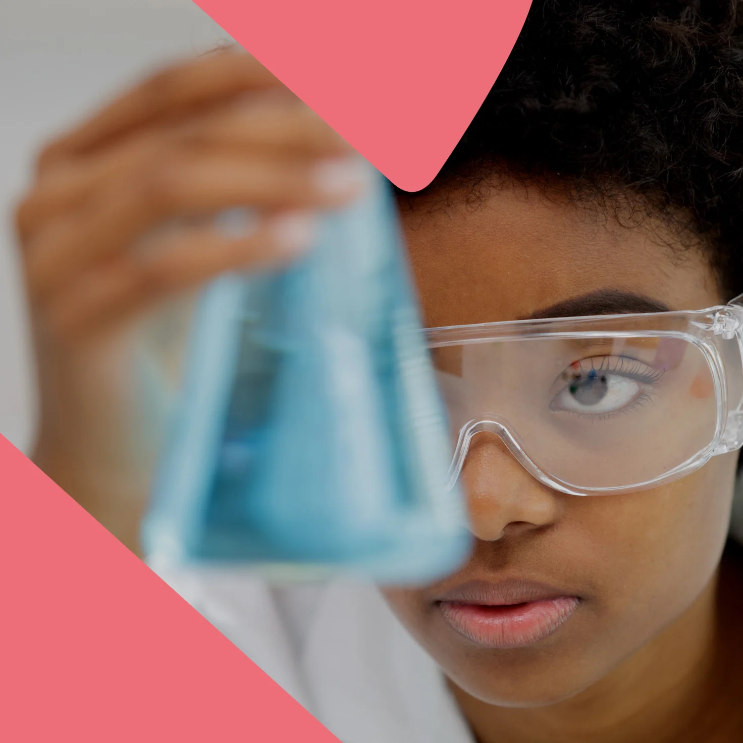 Close-up of a scientist in safety goggles examining a blue liquid in a flask