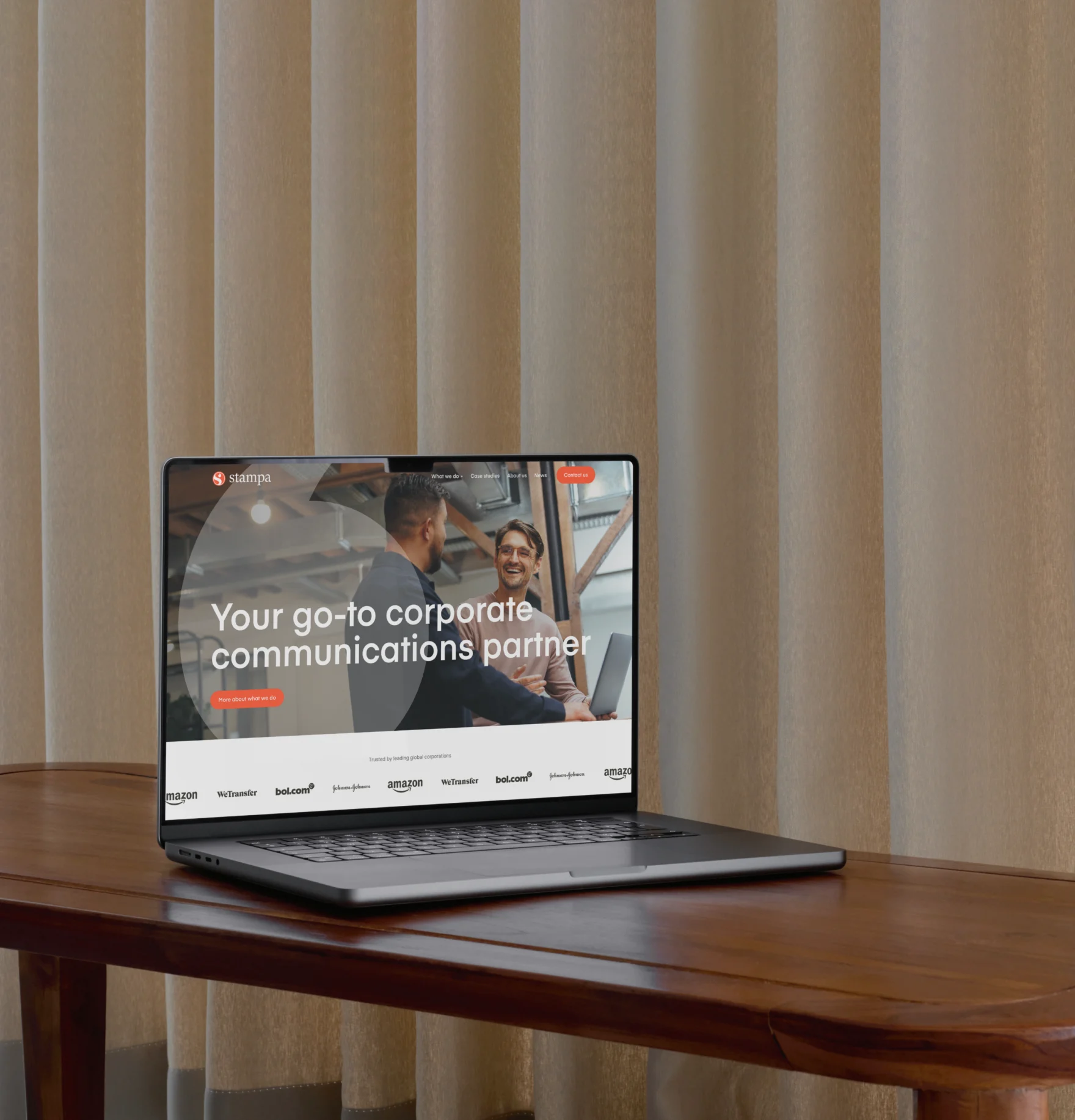 Laptop displaying the Stampa homepage with the tagline 'Your go-to corporate communications partner'