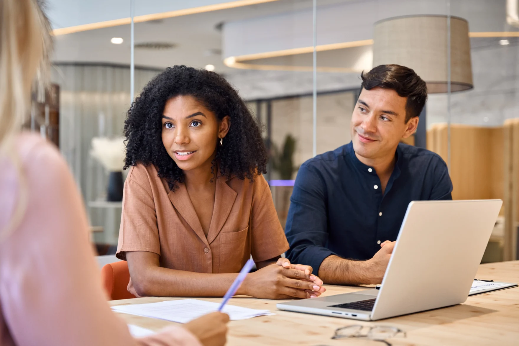 Consultant discussing strategy with two clients in a meeting room