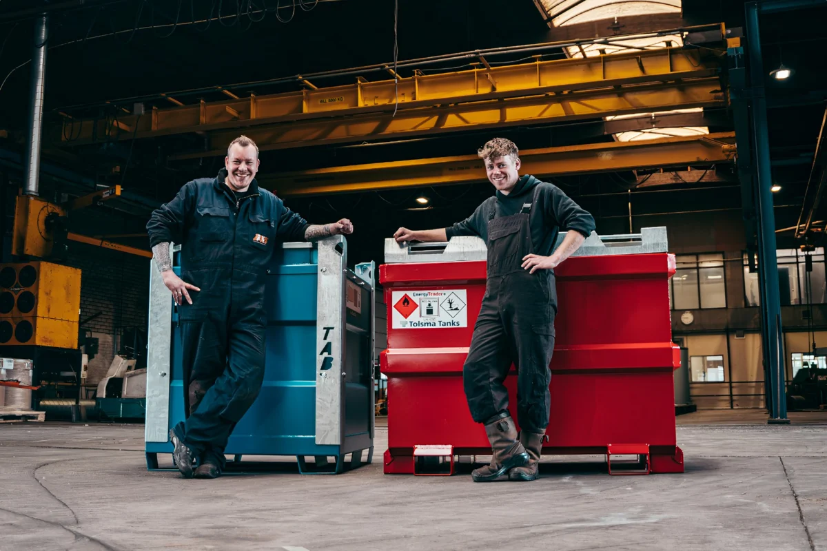 Two factory workers posing beside TAB and Tolsma Tanks equipment