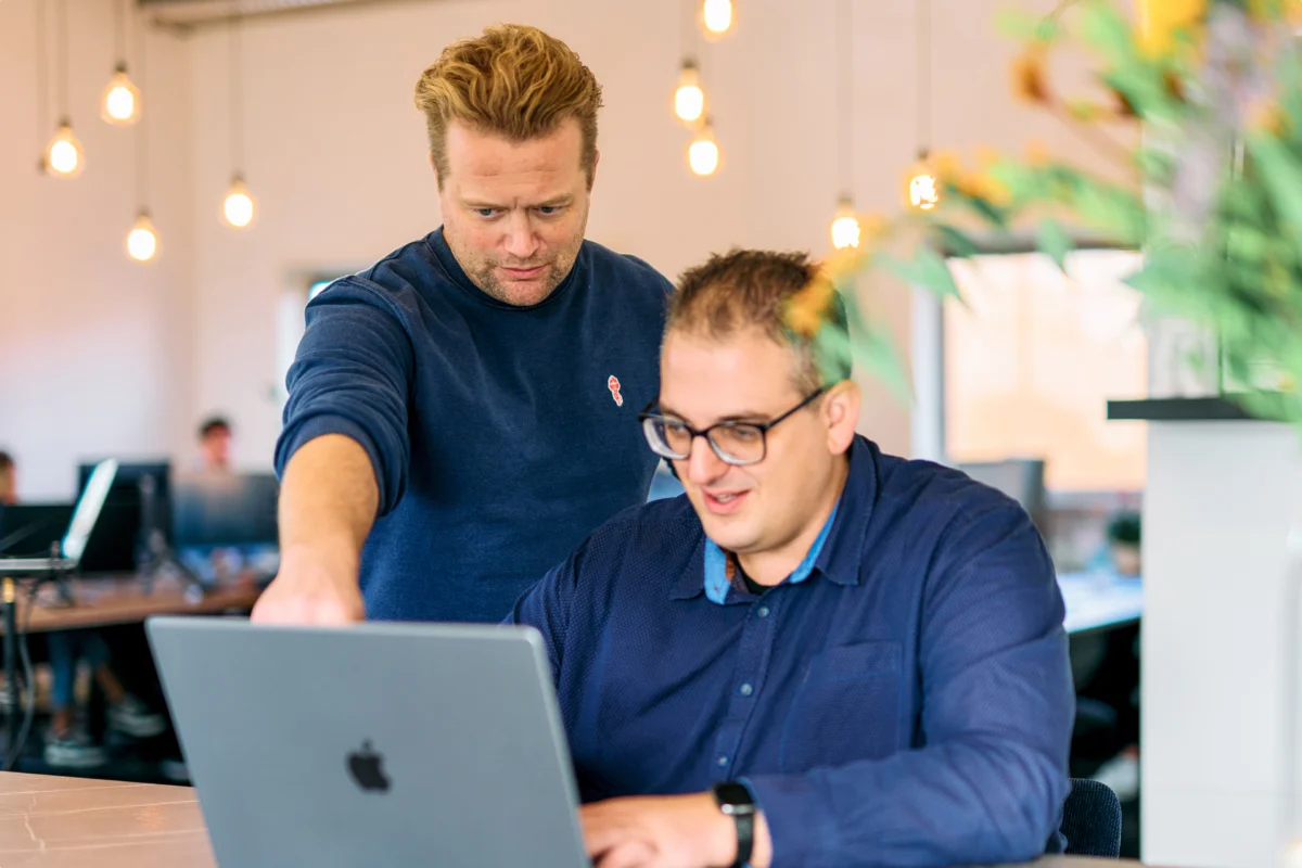 Two colleagues reviewing work together on a laptop in a modern office
