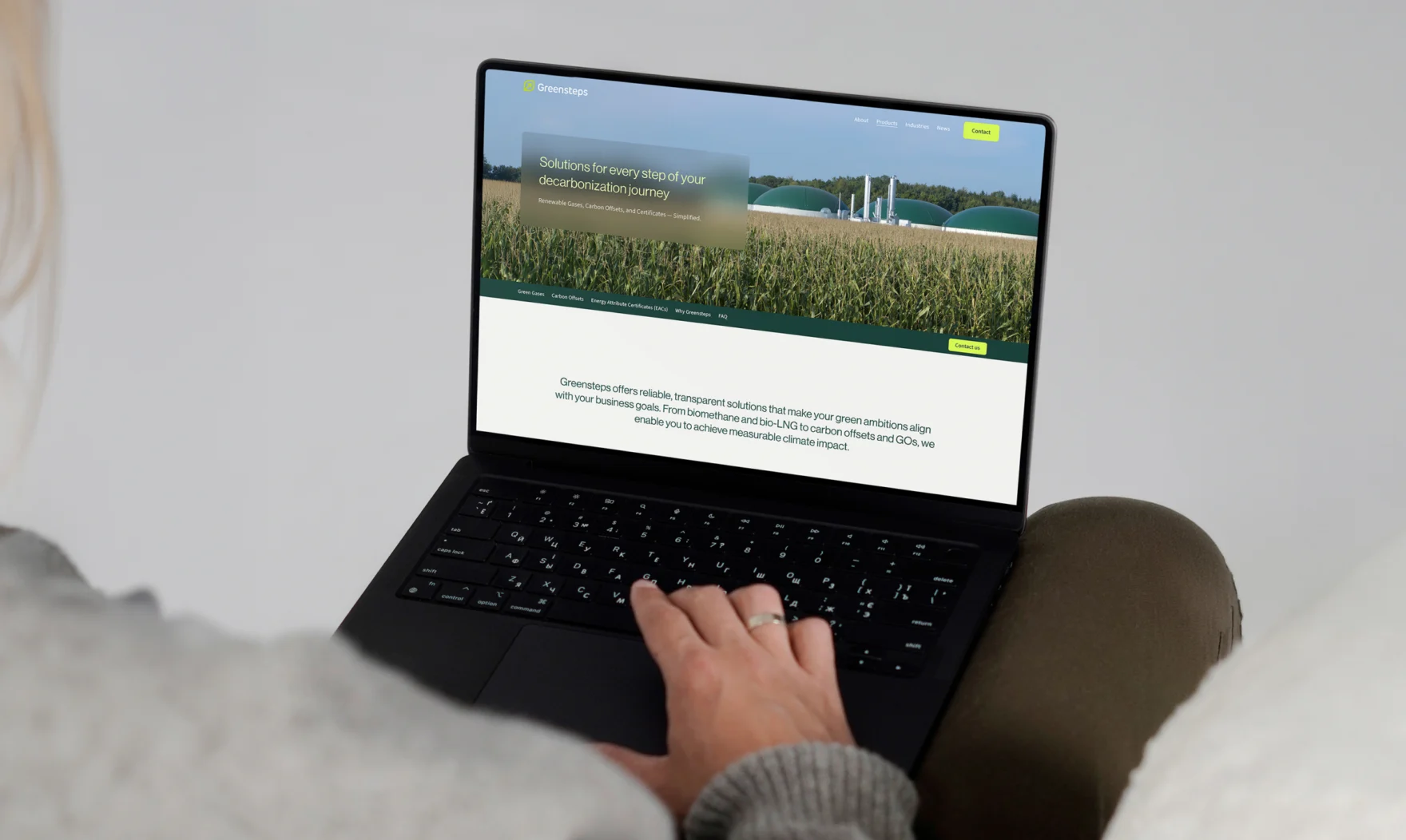 Person using a laptop displaying the homepage of the Greensteps website.